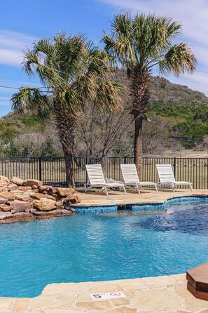 A pool area with lounge chairs and palm trees. - Spacious Vacation Home with Great Outdoor Amenities (Concan)