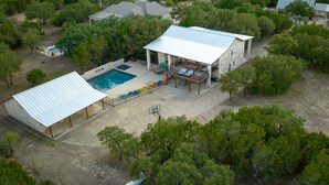 An aerial view of a property with a large house, a swimming pool, and a covered patio area. - Large Lodge located in Mountain Valley (Concan)