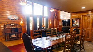 A dining area with a wooden table and chairs, a chandelier, and a sign reading "RIO NICE LODGE." - Large Lodge located in Mountain Valley (Concan)