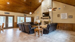 A spacious living room with a stone fireplace, leather sofas, and a wooden ceiling. - Beautiful Vacation Home with GREAT amenities (Concan)