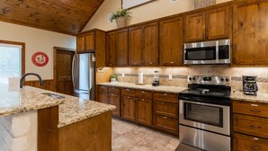 A kitchen with wooden cabinets, a stainless steel refrigerator, a microwave, and an oven. - Beautiful Vacation Home with GREAT amenities (Concan)