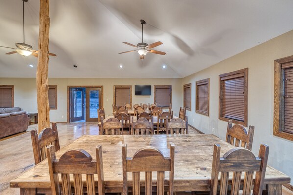 A spacious dining area with a large wooden table and chairs, ceiling fans, and wooden window shutters. - Large Vacation Home with great amenities (Concan)