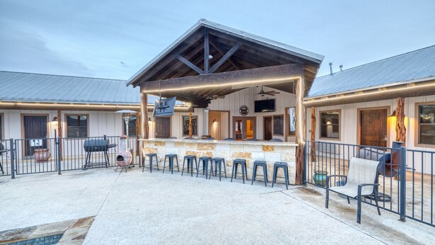 Une terrasse extérieure couverte avec un bar, des sièges et une piscine.