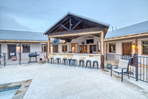 A covered outdoor patio with a bar area, seating, and a pool. - Large Vacation Home with great amenities (Concan)