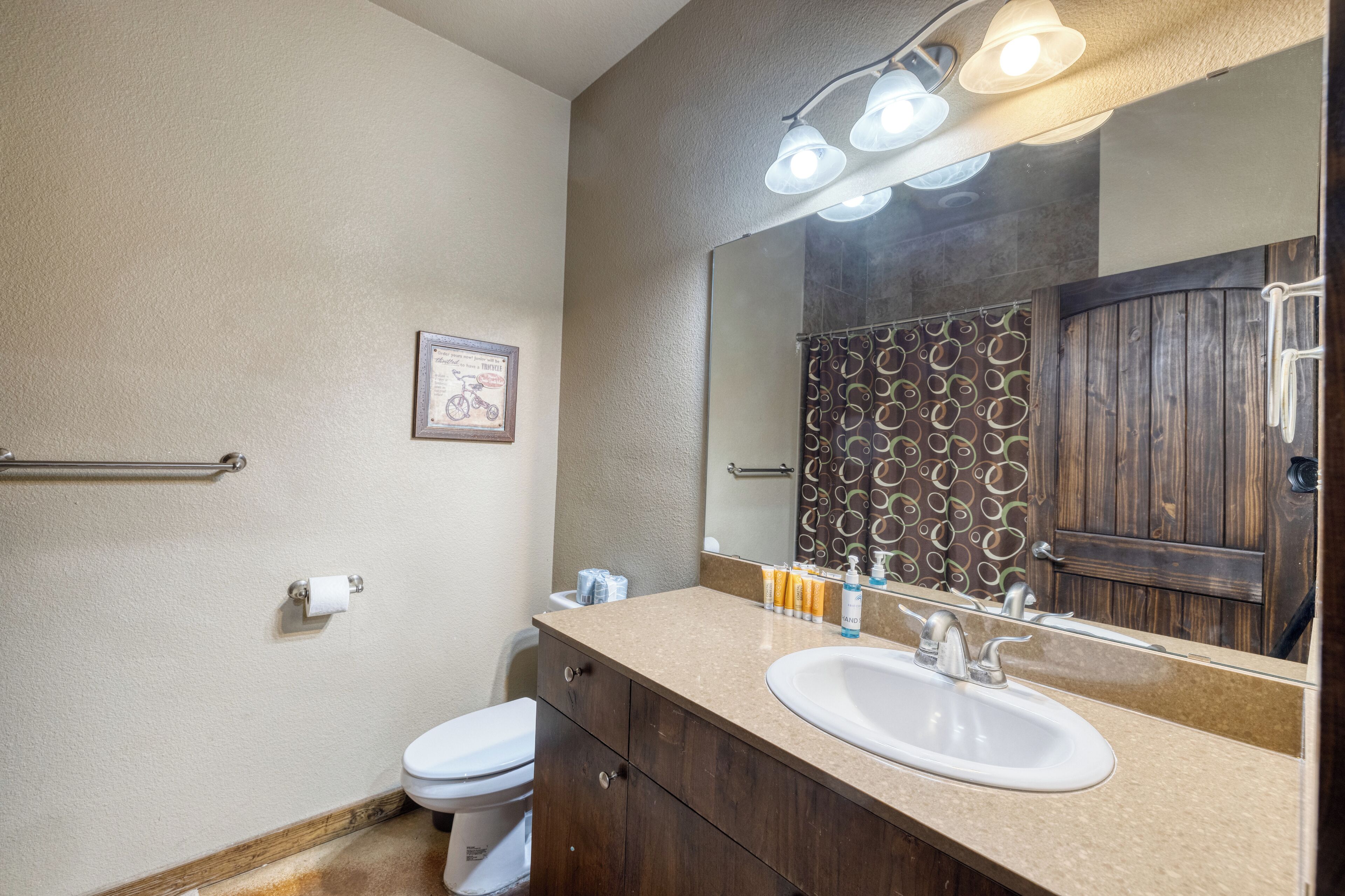 A bathroom with a beige countertop, a white sink, a mirror, and a towel rack.