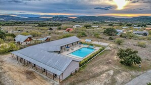 Un grand bâtiment doté d’une piscine, entouré d’un paysage rural avec des collines en arrière-plan.