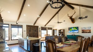 A spacious kitchen with a large island, wooden ceiling beams, and a mounted deer head.