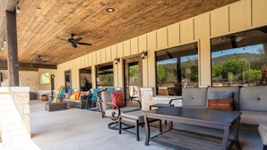 A covered patio area with outdoor seating, including a sofa and chairs, and a table.
