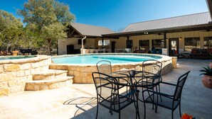 A pool area with stone steps, metal chairs, and a covered patio with seating.