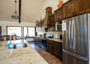 A modern kitchen with granite countertops, stainless steel appliances, and wooden cabinets. - Custom Home located in the beautiful Golf Club of Texas (Concan)