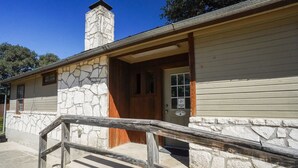 A stone and wood building with a wooden door and a small porch. - Quaint cabin located near the Frio River (Concan)