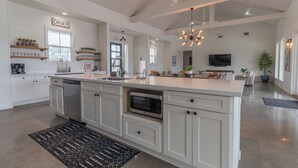 A spacious kitchen with a central island, white cabinetry, and a dining area with a sign labeled "DINER". - Unique Vacation Home located in Concan near the golf course (Concan)