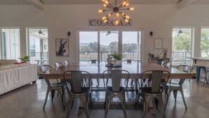 A spacious dining area with a long wooden table and metal chairs, a chandelier, and a view of the outdoors. - Unique Vacation Home located in Concan near the golf course (Concan)