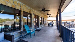 A covered patio with stone walls, outdoor seating, and a pool.
