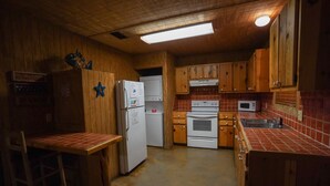 A compact kitchen with wooden cabinets, a refrigerator, a microwave, and a stove. - River Front cabin with access to shared pool! (Concan)