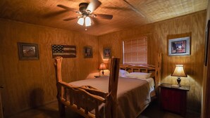 A wooden-paneled bedroom with a four-poster bed, a ceiling fan, and framed pictures on the walls. - River Front cabin with access to shared pool! (Concan)