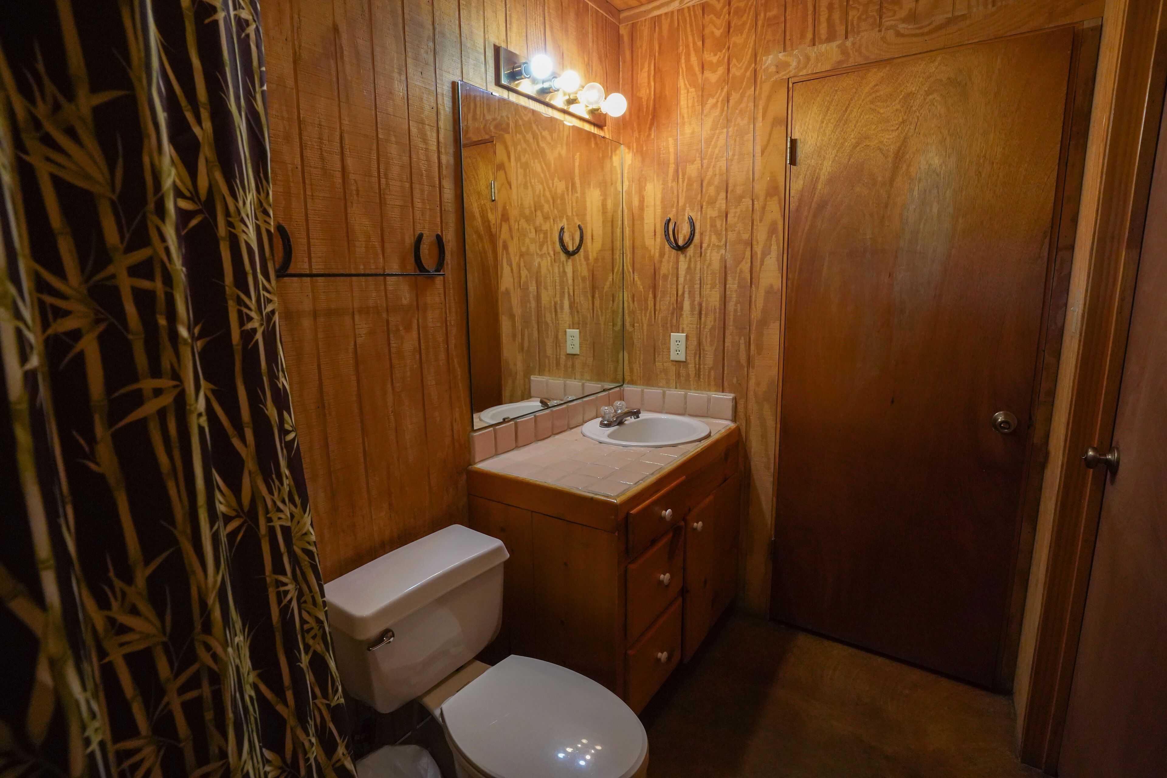 A wooden bathroom with a toilet, sink, and vanity.