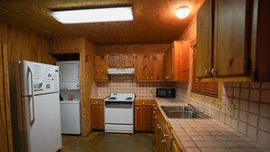 Una cucina compatta con mobili in legno, un frigorifero, un fornello, un forno a microonde e un lavello.