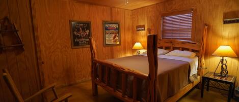 A wooden-themed bedroom with a bed, two bedside lamps, a wooden chair, and a ceiling fan.