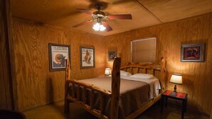 A wooden-paneled room with a bed, a ceiling fan, and framed pictures on the walls. - Walking distance to the Frio River, access to shared pool (Concan)