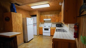 A compact kitchen with wooden cabinets, a refrigerator, a stove, and a microwave. - Walking distance to the Frio River, access to shared pool (Concan)