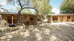 A rustic cabin with a barbecue grill, outdoor seating, and a stone pathway. - Walking distance to the Frio River, access to shared pool (Concan)