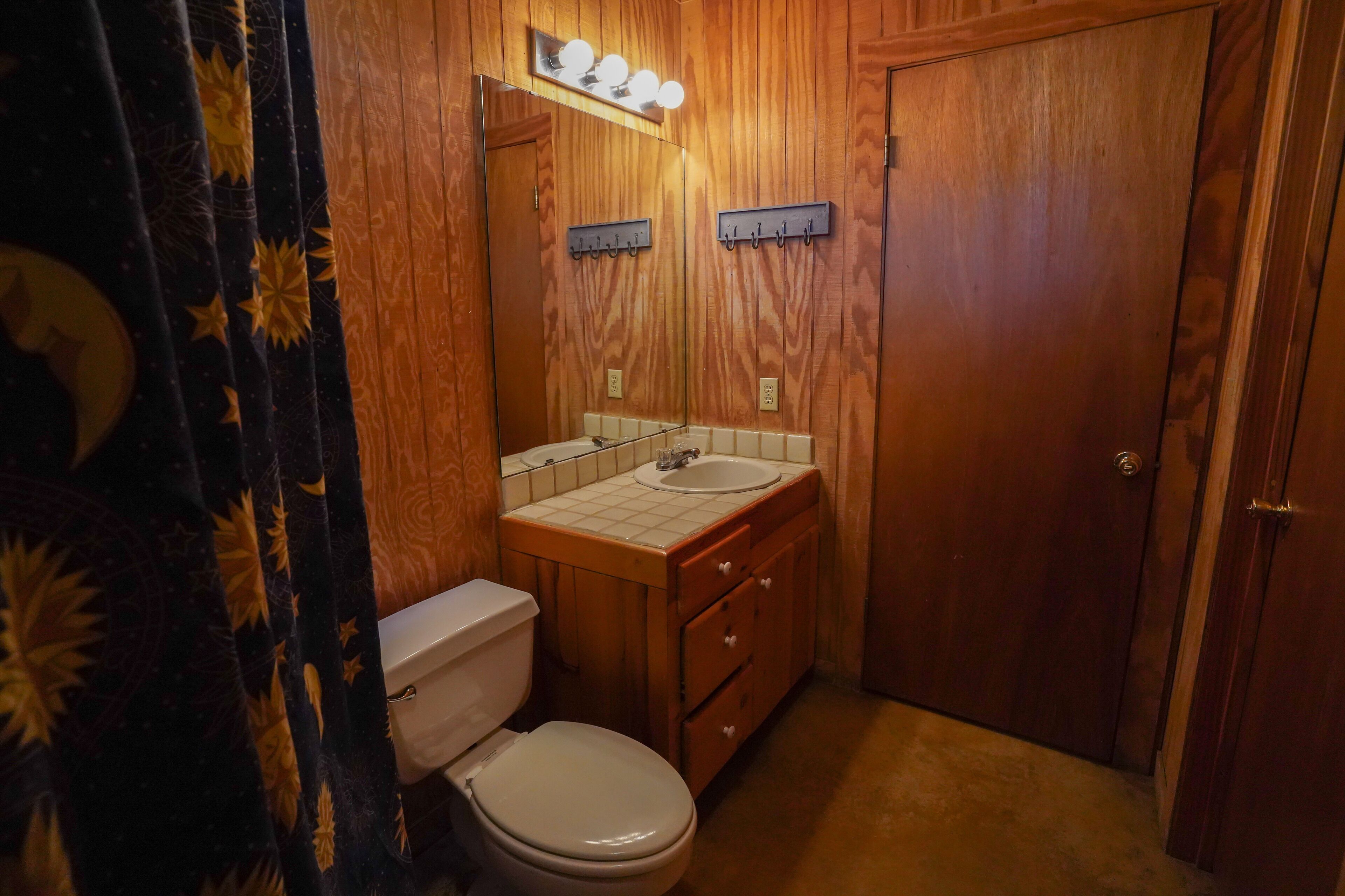 A small, compact bathroom with a toilet, sink, and wooden vanity.