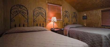 Une chambre avec deux lits, des murs en bois, une fenêtre avec des stores et une lampe de chevet.