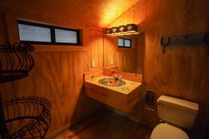 Un baño pequeño de madera con un lavamanos, un inodoro y una ventana.