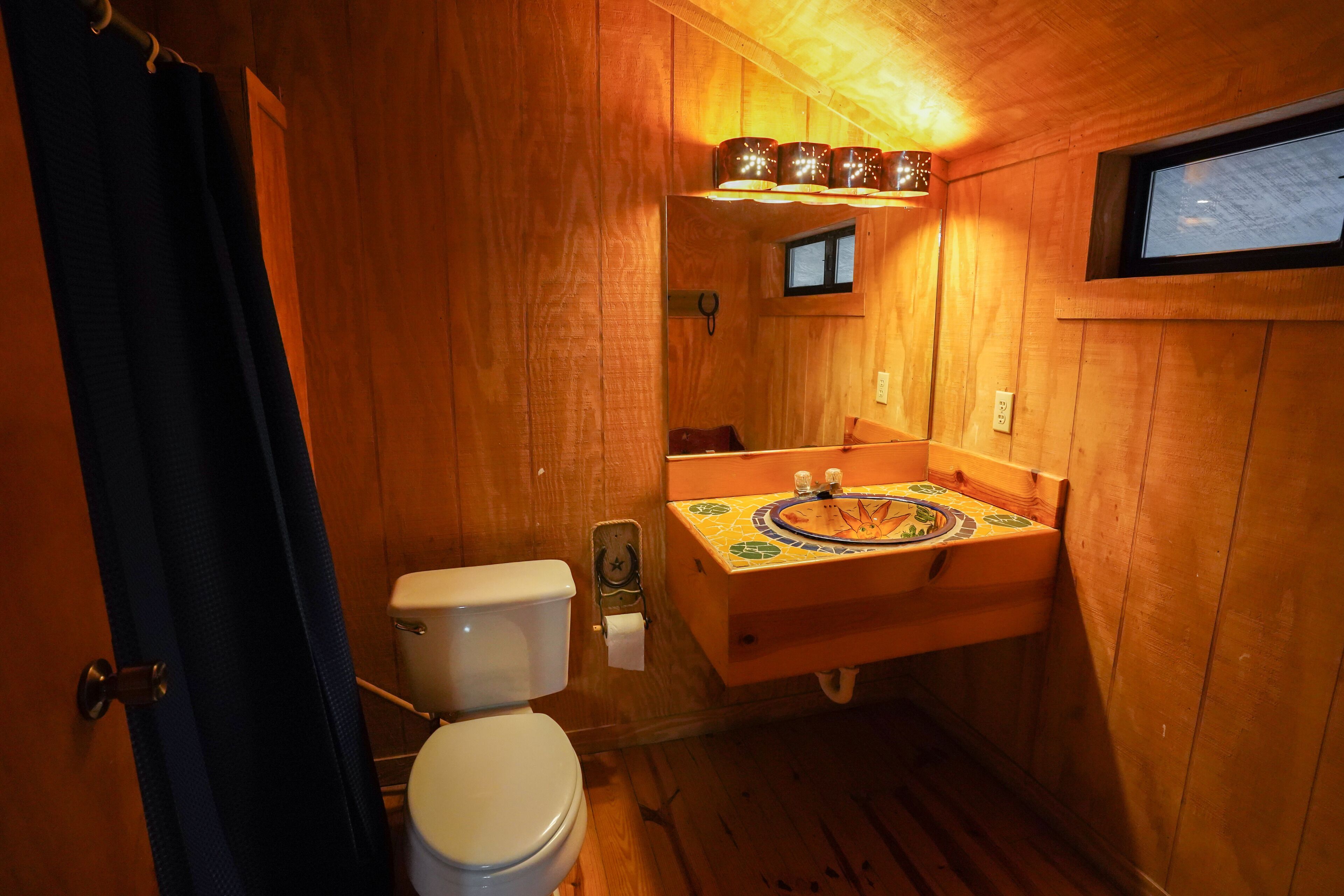Une salle de bain en bois avec des toilettes, un lavabo et une petite fenêtre.