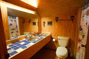 A wooden bathroom with a tiled sink, a toilet, and a mirror. - Riverfront cabin with a pool! (Concan)