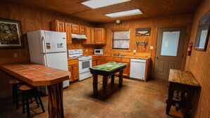 A compact kitchen with wooden cabinets, a refrigerator, a microwave, and a stove. - Riverfront cabin with access to shared pool! (Concan)