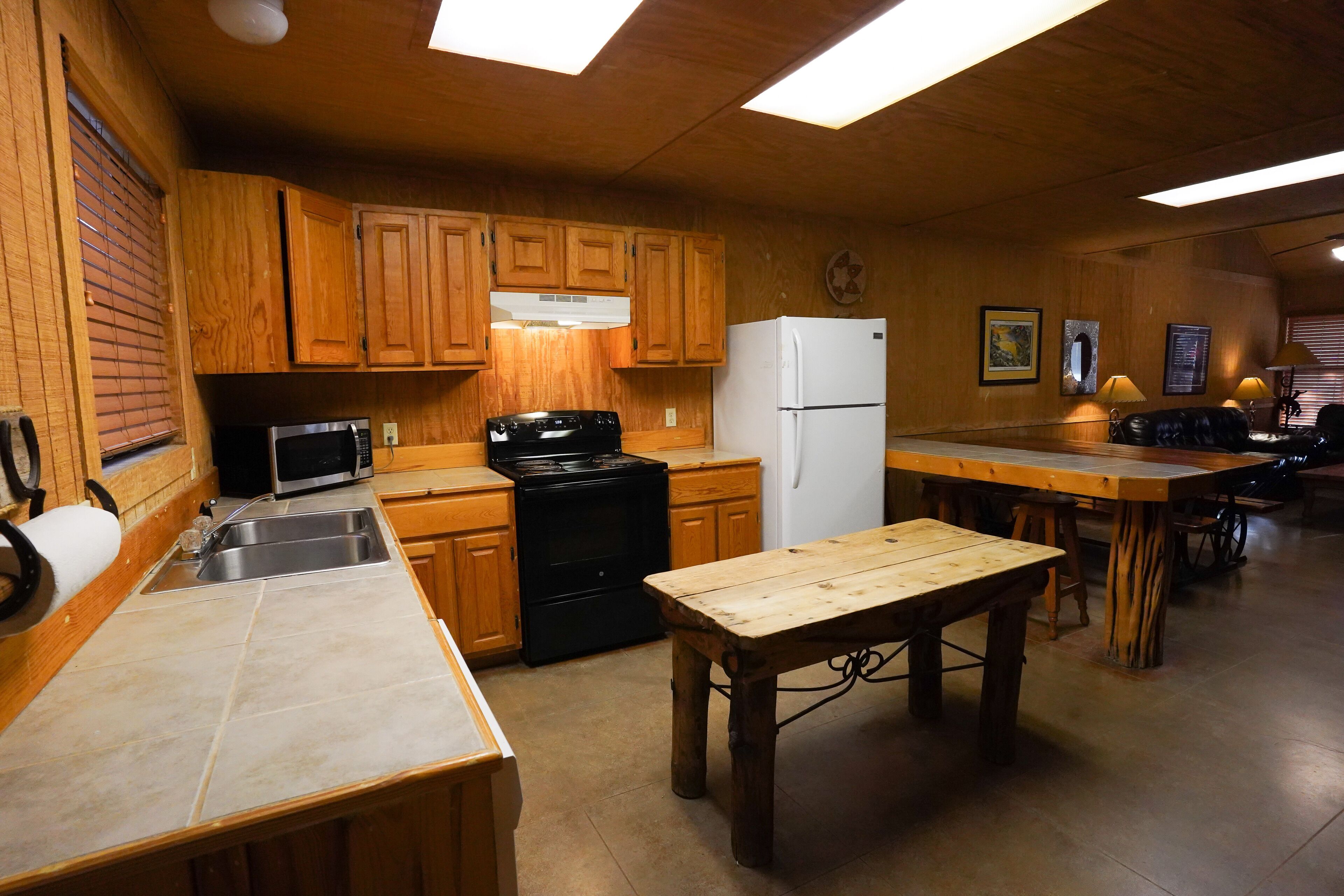 Una cocina con armarios de madera, microondas, estufa y refrigerador.
