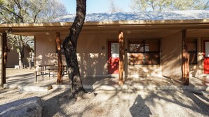 A building with a covered porch, a bench, and a tree in front. - Riverfront cabin with access to shared pool! (Concan)
