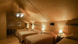 A cozy attic bedroom with three beds, wooden walls, and a ceiling fan. - Riverfront cabin with access to shared pool! (Concan)