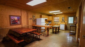 A wooden interior with a kitchen area featuring a wooden table, benches, and a refrigerator. - Riverfront cabin with access to shared pool! (Concan)