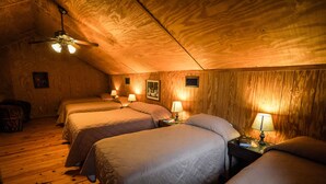 A cozy attic bedroom with three beds, wooden walls, and a ceiling fan. - Riverfront cabin with access to shared pool! (Concan)