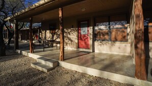 A building with a covered porch, concrete steps, and a red door. - Riverfront cabin with access to shared pool! (Concan)