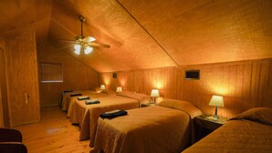 A room with four single beds, wooden walls, a ceiling fan, and a window with blinds. - Riverfront cabin with access to shared pool! (Concan)