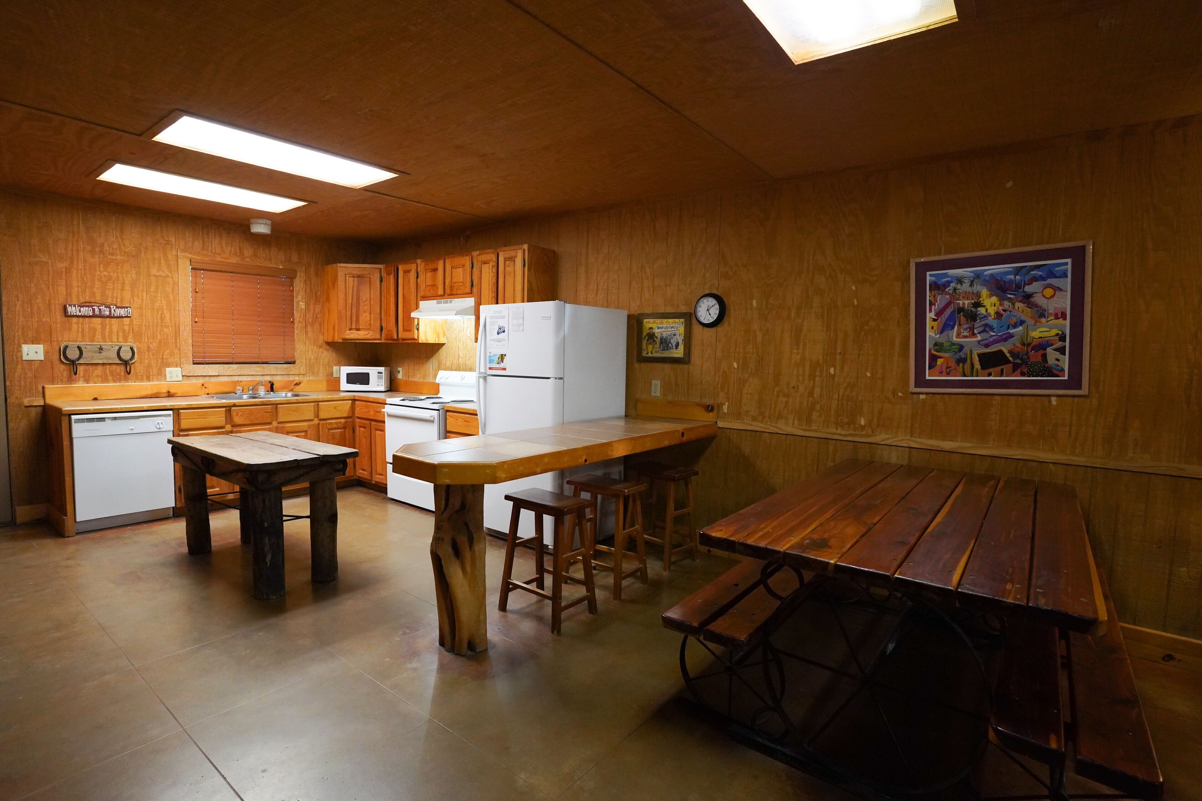 A kitchen with wooden cabinets, a white refrigerator, a wooden dining table, and a bench.