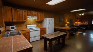 A kitchen with wooden cabinets, a white stove, a refrigerator, and a wooden dining table. - Riverfront cabin with access to shared pool! (Concan)