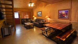 A cozy living room with a wooden ceiling, a sofa set, a wooden table with benches, and a ceiling fan. - Riverfront cabin with access to shared pool! (Concan)