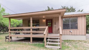 A small, single-story building with a porch, a red door, and a window. - Frio Country Resort - Within walking distance to the Frio River! (Concan)