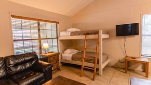 A bunk bed with a TV, a wooden table, a couch, and a window with blinds. - Frio Country Resort - Within walking distance to the Frio River! (Concan)