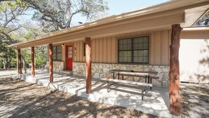 A building with a covered porch, stone walls, and a red door. - Frio Country Resort - Within walking distance to the Frio River! (Concan)