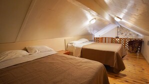 A cozy attic bedroom with two beds, wooden flooring, and a sloped ceiling. - Frio Country Resort - Within walking distance to the Frio River! (Concan)