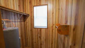 Ein kleiner Raum mit Holzwänden, einem Fenster, einem Waschbecken und einer Toilette.