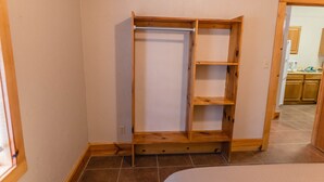 A room with a wooden wardrobe, a bed, and a kitchen area in the background. - Frio Country Resort - Within walking distance to the Frio River! (Concan)