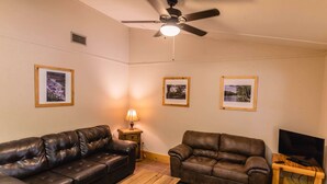 A living room with two leather sofas, a wooden coffee table, a ceiling fan, and framed pictures on the walls. - Frio Country Resort - Within walking distance to the Frio River! (Concan)