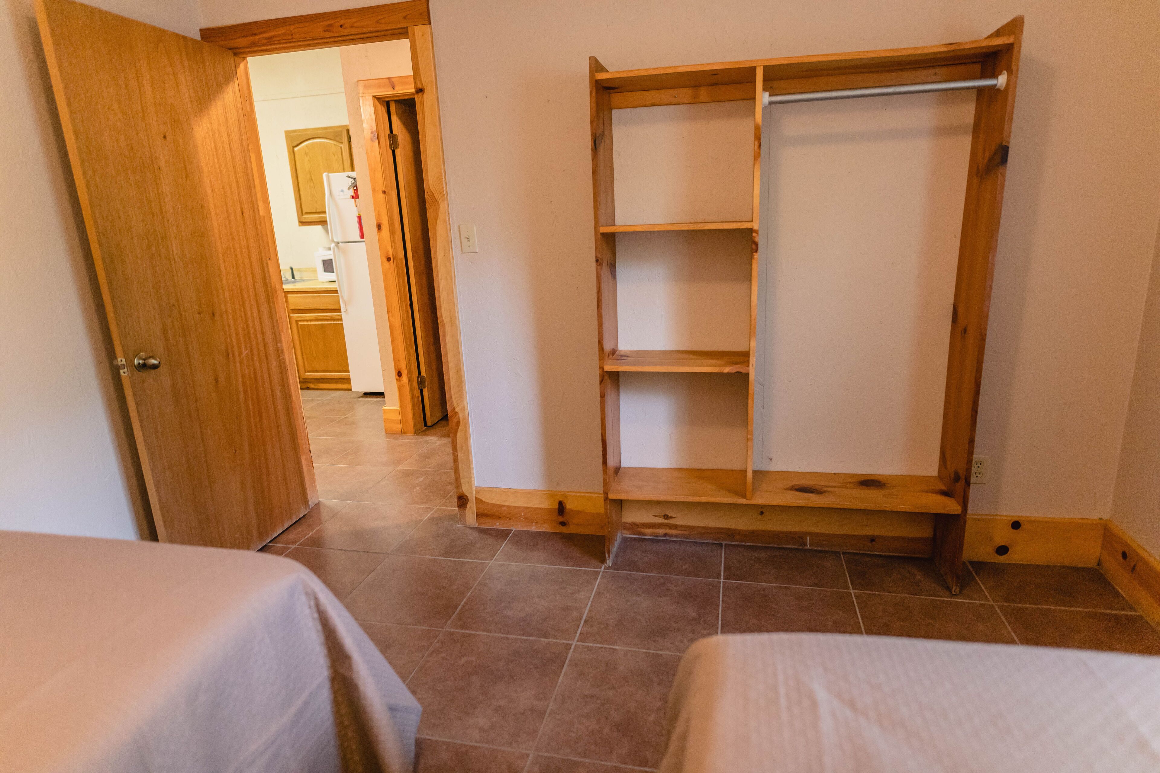 Una camera da letto con due letti, un'armadio in legno e un pavimento piastrellato.